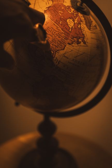 Hand pointing to a country on an antique globe