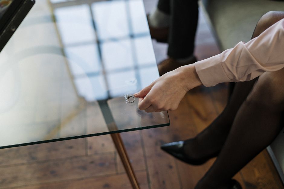 Femme retirant son alliance et la posant sur une table en verre