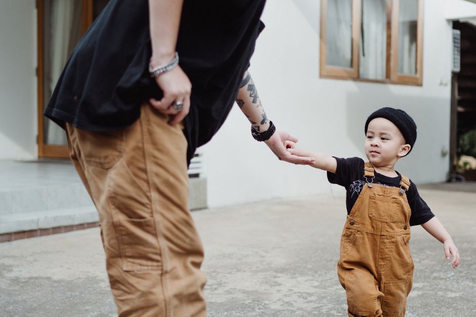 Jeune enfant tenant la main d'un parent