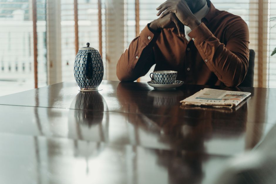 Cliente esperando en una mesa con una taza de té y un periódico