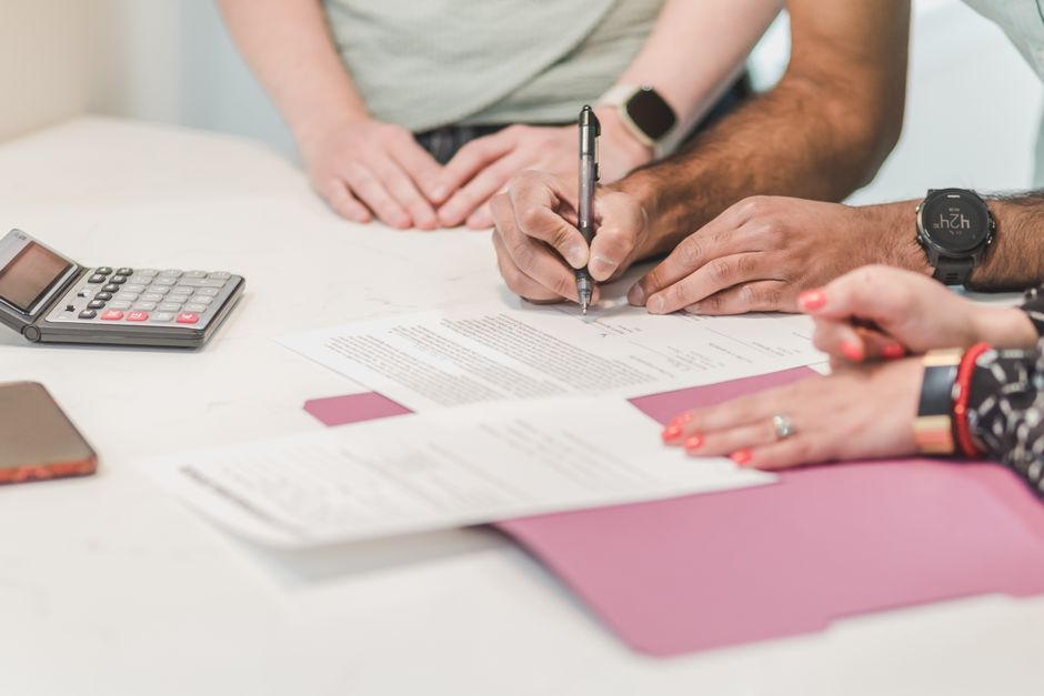 Documents de travail, calculatrice et signature réunis sur une table