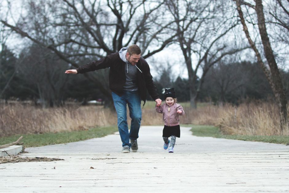 Padre e hija caminando juntos por un sendero de un parque